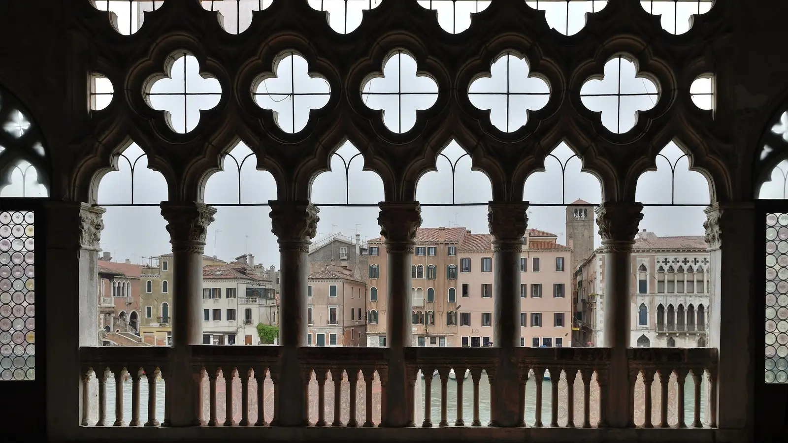 Historic Venetian palazzo suite with arched Gothic windows overlooking gondolas along the Grand Canal.